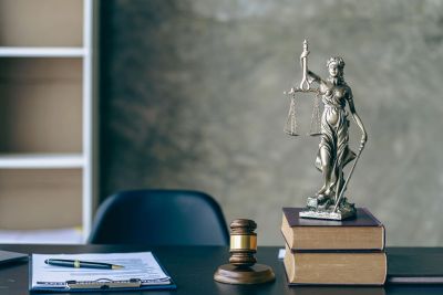 Lady Justice statue on books with gavel and legal documents.
