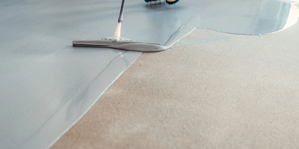 Applying a liquid coating on a floor with a squeegee.