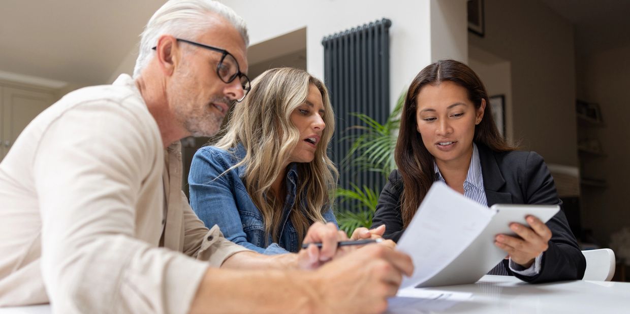 Three people discussing documents at a table.