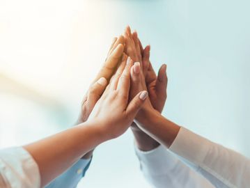 Group of people giving a high five symbolizing teamwork and unity.