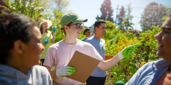 Jeune homme avec un clipboard donnant des instructions lors d'un jardin communautaire.