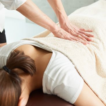 Person receiving a back massage under a beige blanket.
