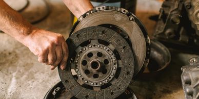 A mechanic holds a clutch disc during car repair work.