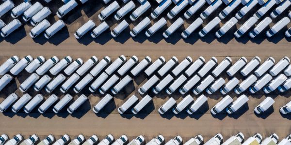 Aerial view of numerous white trucks parked in neat rows.