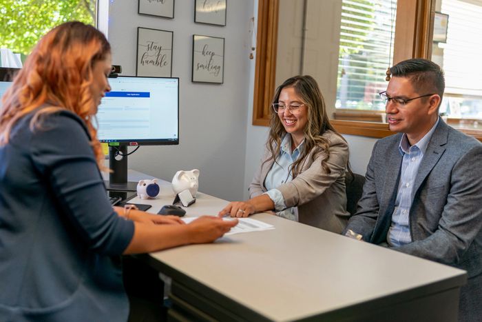 Outdoor patio with dining set and grill under a yellow shade sail.