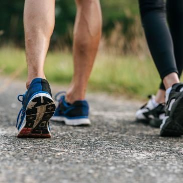Two people walking on a gravel path wearing sneakers.