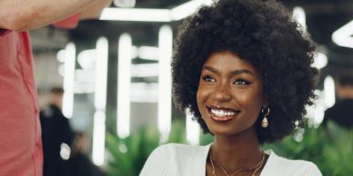 A smiling woman with curly hair and elegant earrings in a modern setting.