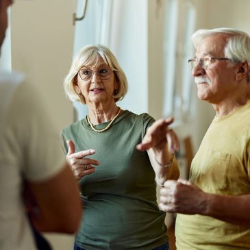 Elderly woman and man engaged in conversation indoors.