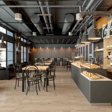 Modern coffee shop interior with tables and pastry display.