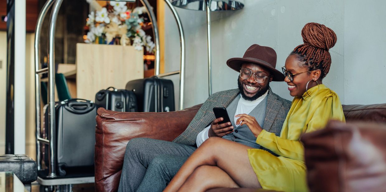 Couple enjoying time together on a couch, looking at a phone and smiling.