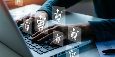 Person shopping online on a laptop with shopping cart icons.