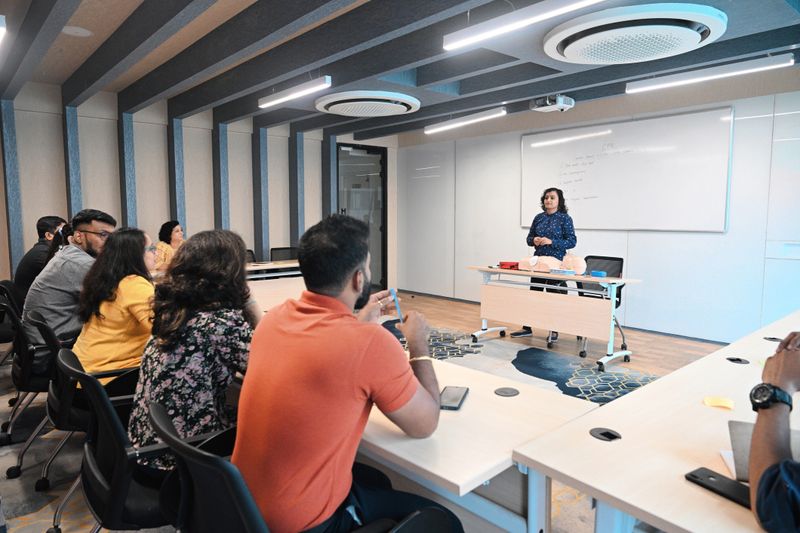 Group of mature adults listening to female instructor explaining CPR; First aid CPR training