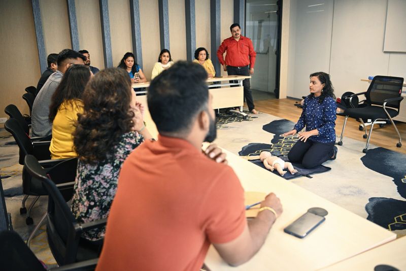 Group of mature adults listening to female instructorexplaining Child CPR during first aid training