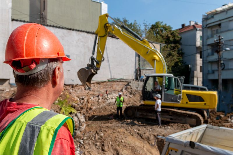 Site manager   standing at the construction site, supervising, inspecting or overseeing the work progress.Process of demolition of old building dismantling. Destruction of dilapidated housing for new development