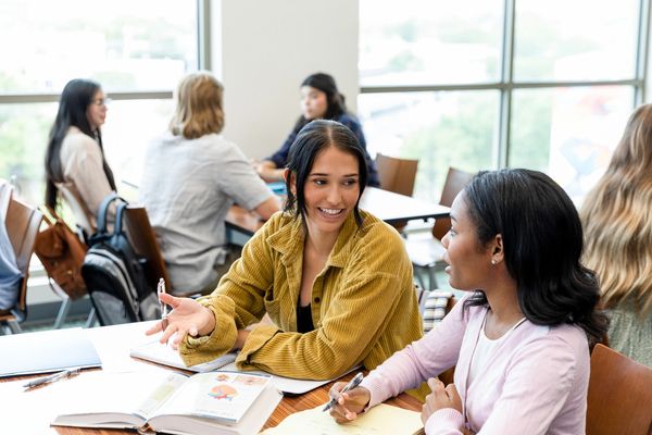  Two women studying at table.
