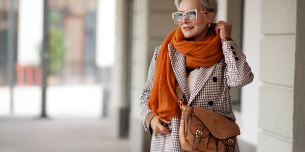 Stylish woman in sunglasses and orange scarf.