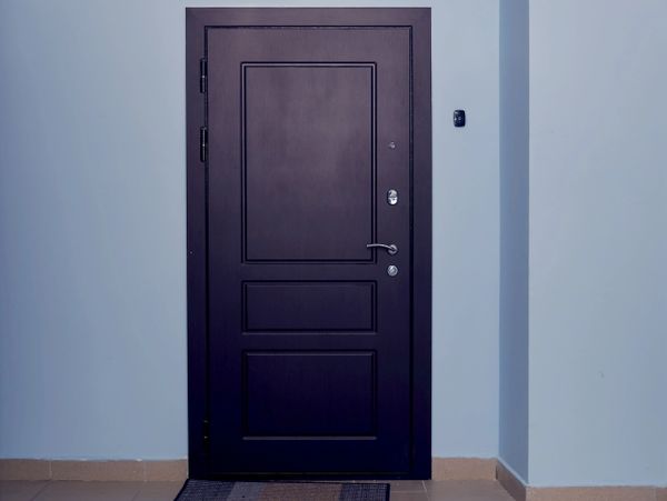 A closed dark-colored door set in a light blue wall.