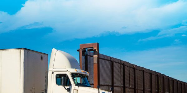 A white semi-truck with a large trailer on a clear day.