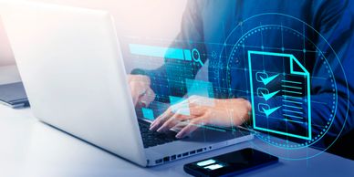 Person working on laptop with digital checklist overlay and smartphone on desk.