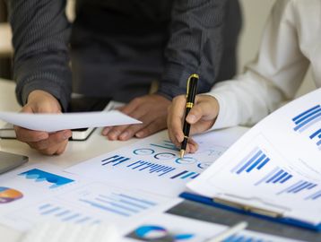 Two people analyzing financial charts and graphs during a business meeting.