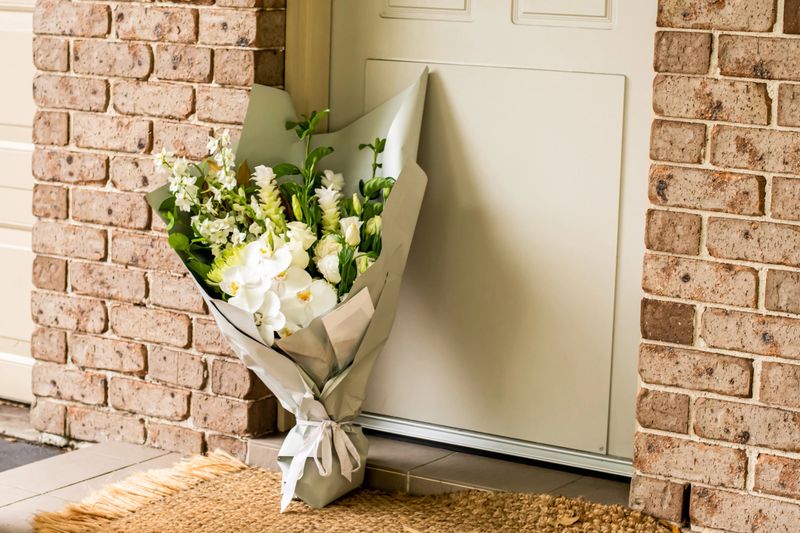 A bouquet of flowers delivered on a porch doorsteps of a house front door. Surprise contactless delivery. Mother's Day, Valentine's Day, Birthday, Anniversary and Celebration
