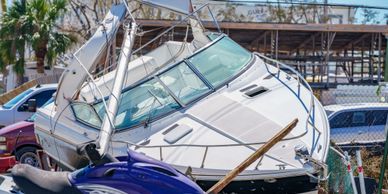 A white boat docked near vehicles and motorcycles.