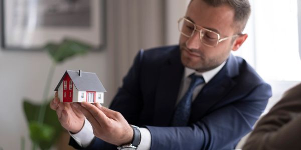 Man in suit holding a miniature house model.