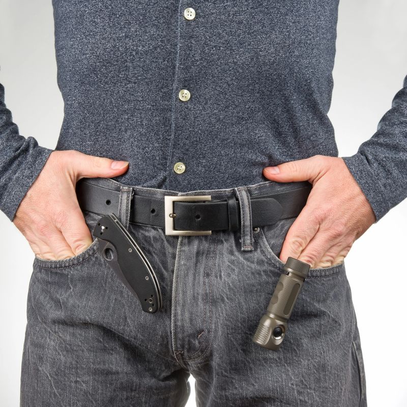 man in jeans on a leather belt with a flashlight and a knife. survival items.