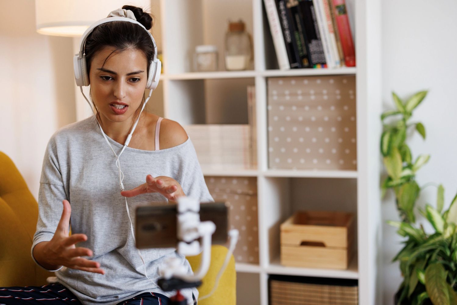 Woman with headphones video chatting on smartphone at home.