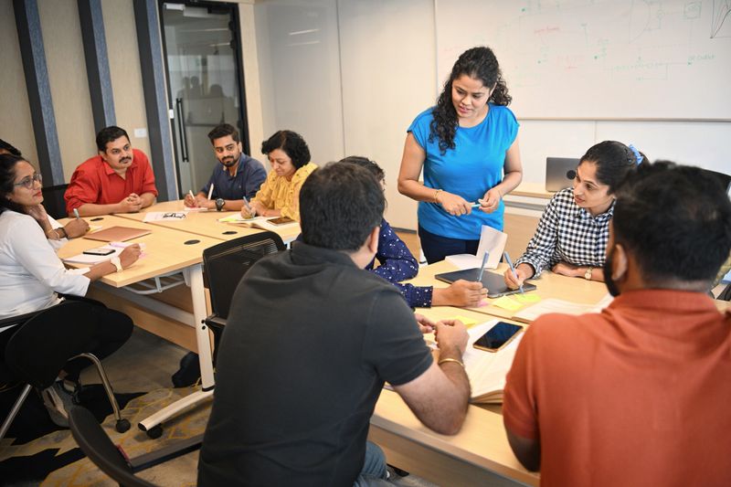 Mature adult participants discussing in teams sitting around desk during the workshop in the classroom