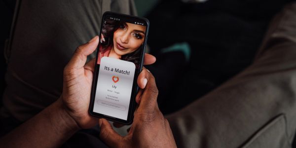 Person holding phone with a dating app match screen.
