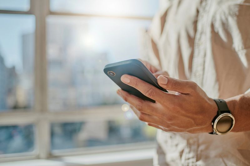 Man typing on smartphone, social media manager working in city office building and contact us on digital communication. Online professional posting, check wifi application and reading business email
