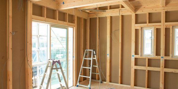 Interior of a wooden frame house under construction with ladders.