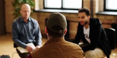 Three men engaged in a conversation indoors.