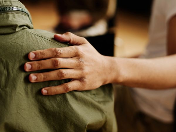 A person comforting another with a hand on their shoulder.