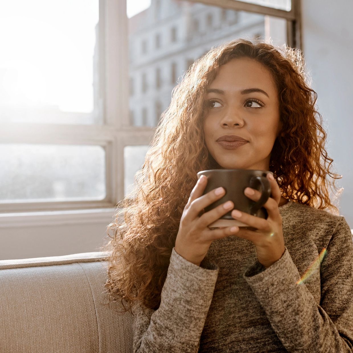 Woman enjoying a warm drink by the window.