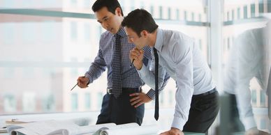 Two businessmen reviewing blueprints in a modern office.