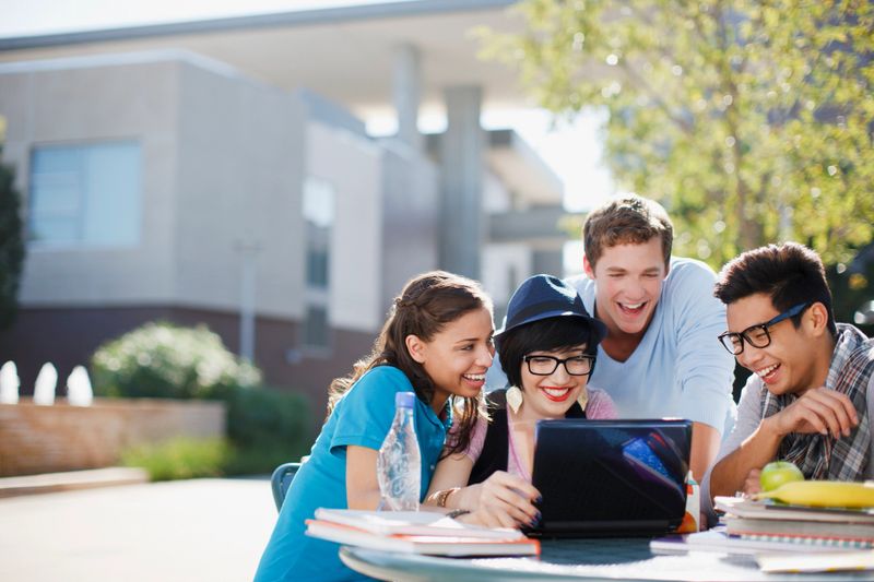 Students using laptop together outdoors