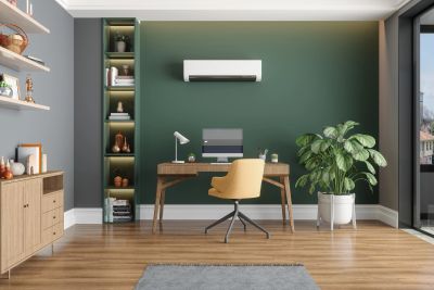 Modern home office with wooden desk, yellow chair, green accent wall, and large plant.
