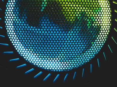 Close-up of a circular grill with blue and green lighting behind.