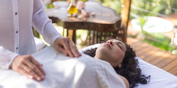 A woman receiving a relaxing neck and shoulder massage while lying on a bed.
