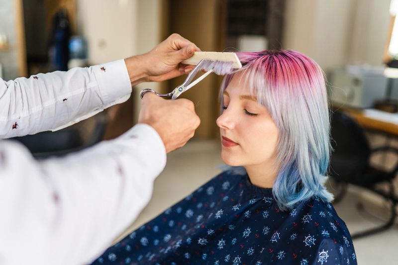 Young woman with colored hair getting a haircut at the hairdresser