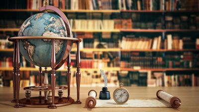 Antique globe and compass on wooden table in a library.