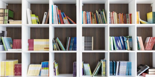 Books neatly arranged on white shelves.