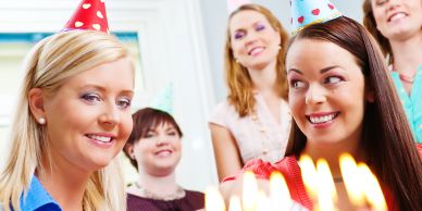 Women celebrating a birthday with party hats and cake.