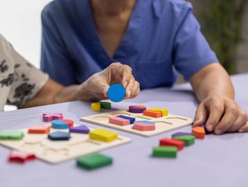 A caregiver working with a client on memory by doing puzzles. 