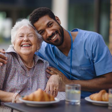 Happy elderly woman with a caring healthcare worker sharing a joyful moment.