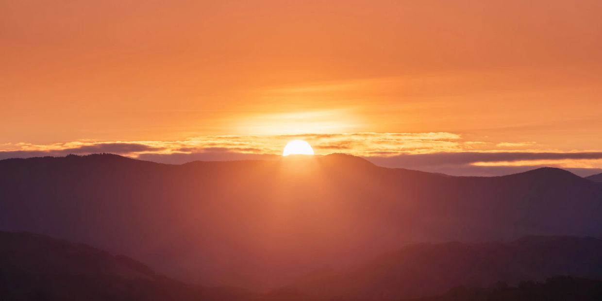 Sunset over mountain ridges with vibrant orange and yellow hues.