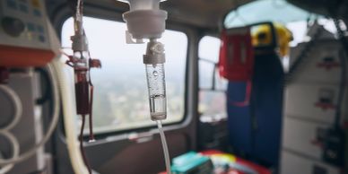 IV drip inside an ambulance with blurred emergency medical equipment in the background.