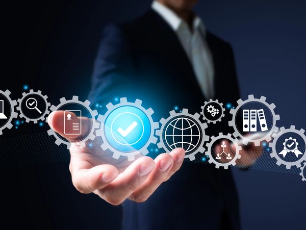 Businessman presenting digital gears with icons representing management and quality.